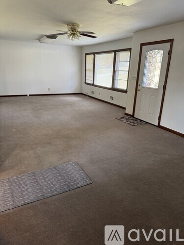 A room with a ceiling fan and a rug on the floor.
