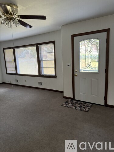 A room with a ceiling fan and a door with a stained glass window.