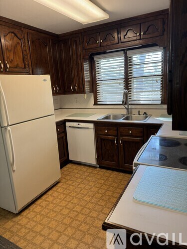 A kitchen with a white refrigerator and brown cabinets.