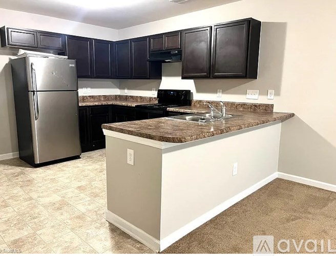 A kitchen with a granite countertop and a refrigerator.