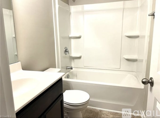 A white toilet sits next to a white sink in a white bathroom.