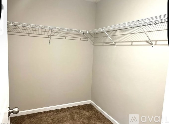 A room with a carpeted floor and a wall-mounted shelf.