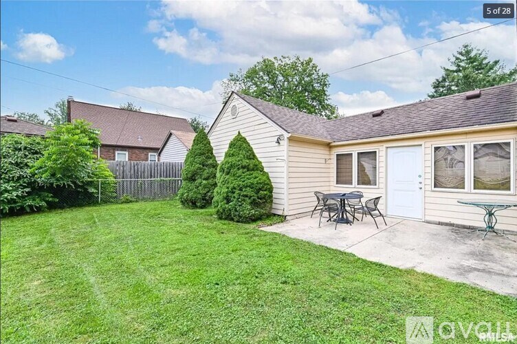 A house with a white garage door and a patio table set outside.