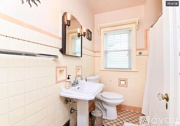 A bathroom with a toilet, sink, and mirror.