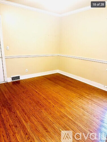 A room with wooden flooring and a wall-mounted air vent.
