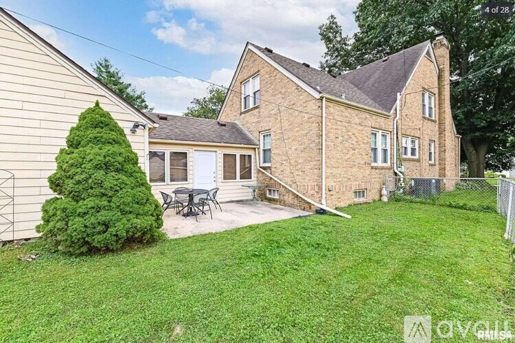 A house with a brown brick exterior and a white door is surrounded by a green lawn.