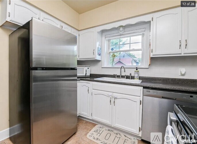 A kitchen with white cabinets and a stainless steel refrigerator.
