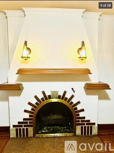 A fireplace with a white wall and two lights above it.