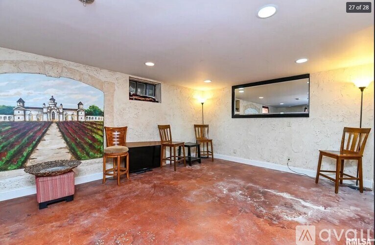 A room with a mural of a landscape and a table with chairs.