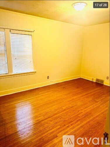 A room with wooden flooring and a window with blinds.