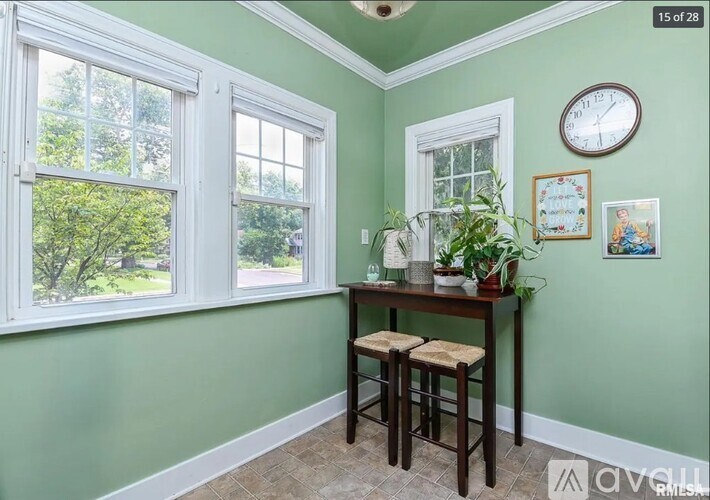 A room with a table and two stools in front of a window.
