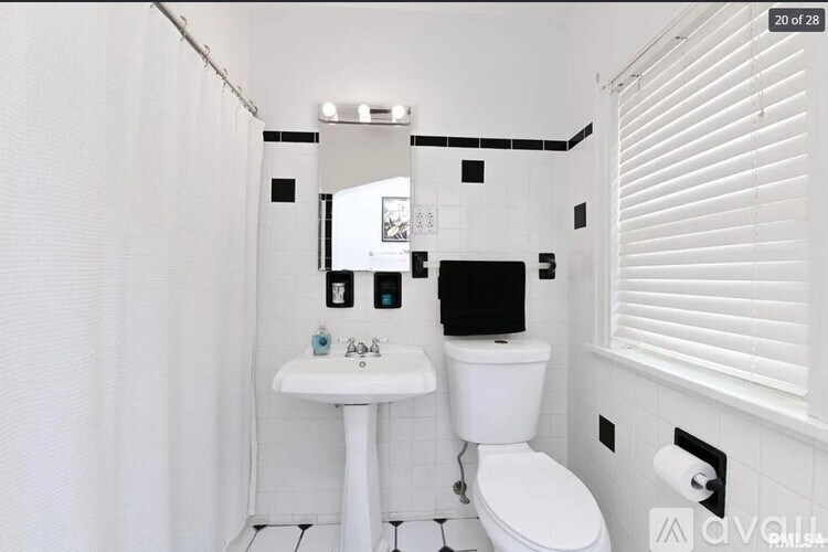 A white bathroom with a toilet, sink, and mirror.