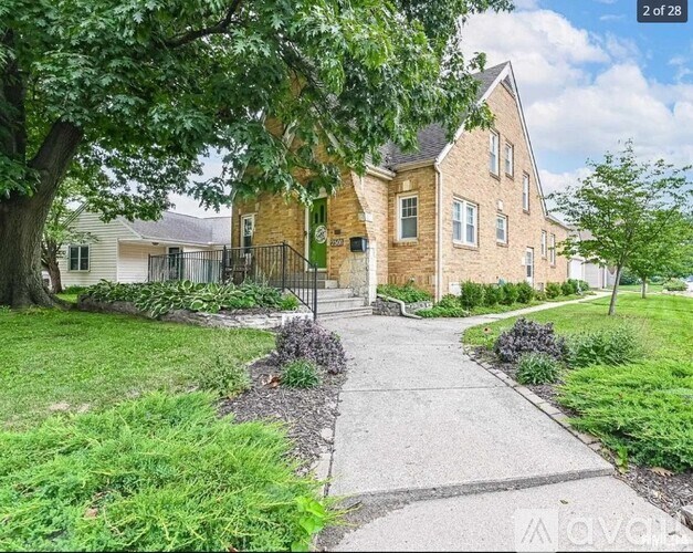 A house with a front yard and a tree in front of it.