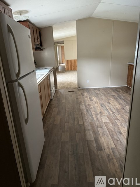 A kitchen with a refrigerator and wooden floors.
