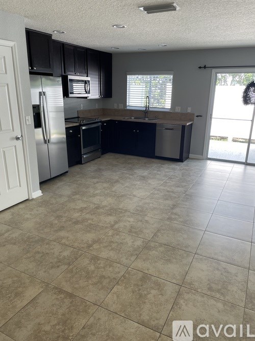 A kitchen with tile flooring and a refrigerator.