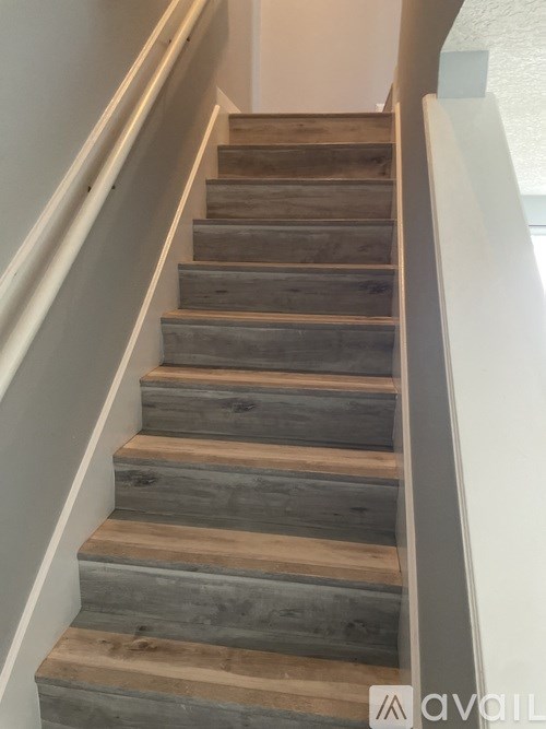 A set of wooden stairs with a white railing.