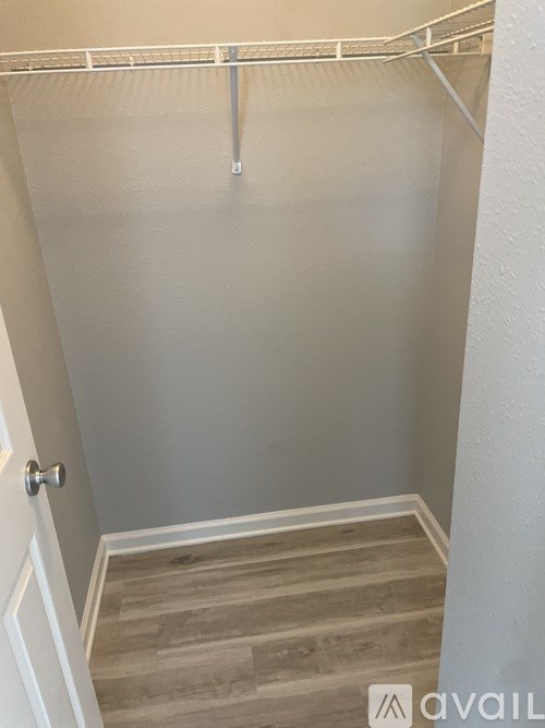A white closet with a door and a shelf.