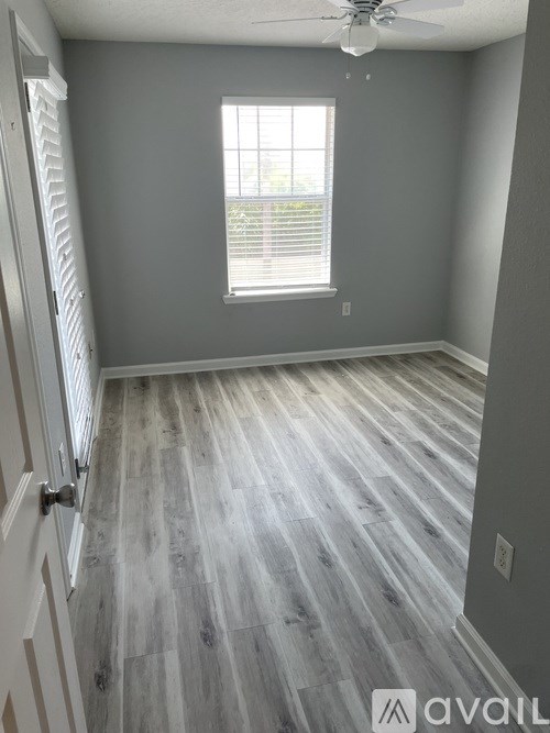 A room with a wooden floor and a window with blinds.