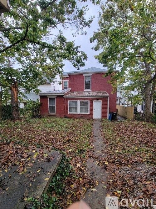 A red house surrounded by trees and fallen leaves.