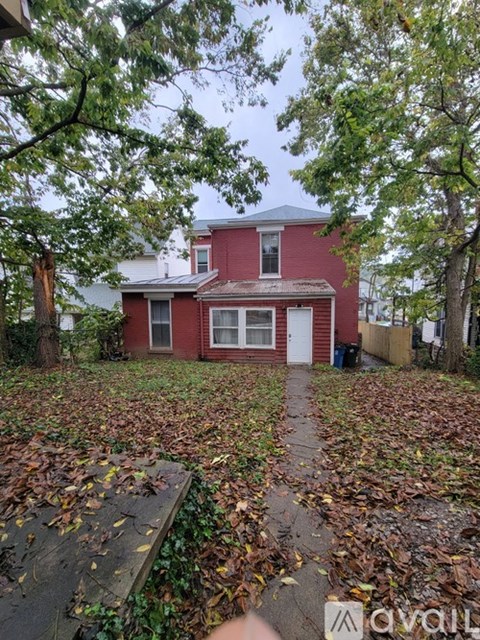 A red house surrounded by trees and fallen leaves.