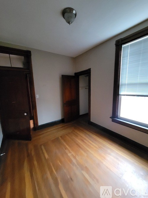 A room with wooden floors and a window with blinds.