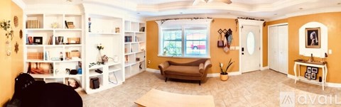 A living room with a brown couch and a white bookshelf.