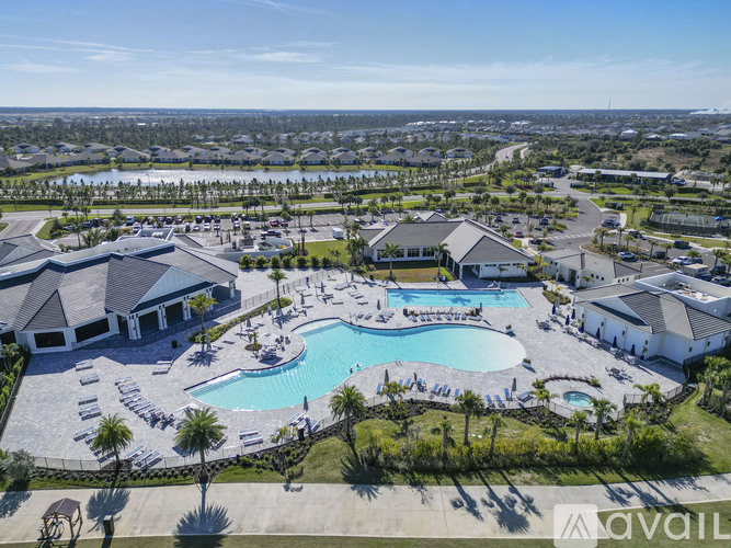 A large outdoor swimming pool surrounded by a grassy area and a building in the background.