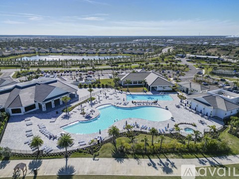 A large outdoor swimming pool surrounded by a grassy area and a building in the background.