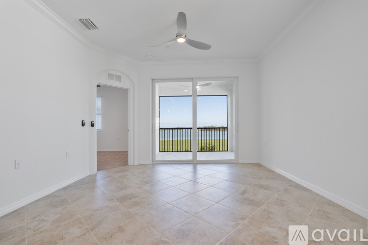 A spacious room with a ceiling fan and a sliding glass door leading to a balcony.