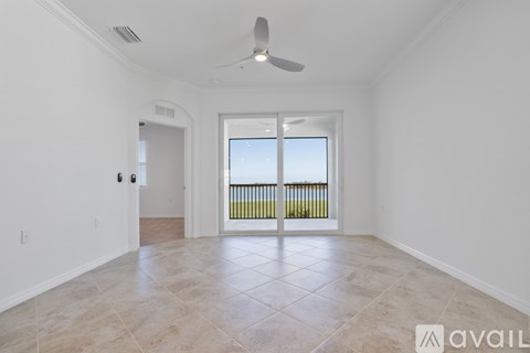 A spacious room with a ceiling fan and a sliding glass door leading to a balcony.