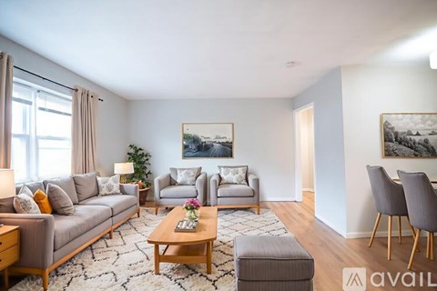 A living room with a grey sofa, two chairs, a coffee table, and a painting on the wall.