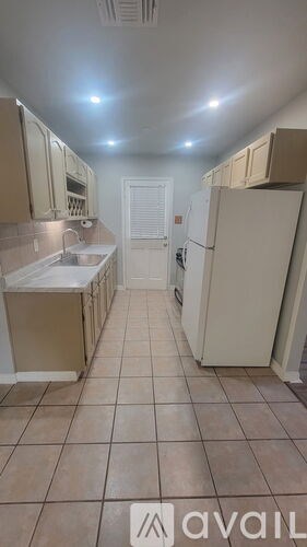 A kitchen with a refrigerator, sink, and cabinets.