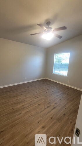 A room with a ceiling fan and wooden flooring.