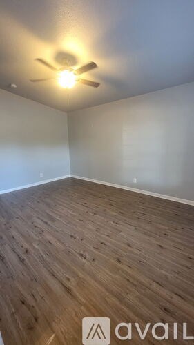 A room with a ceiling fan and wooden flooring.