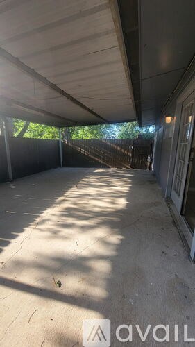 A long, empty, covered concrete area with sunlight shining through.