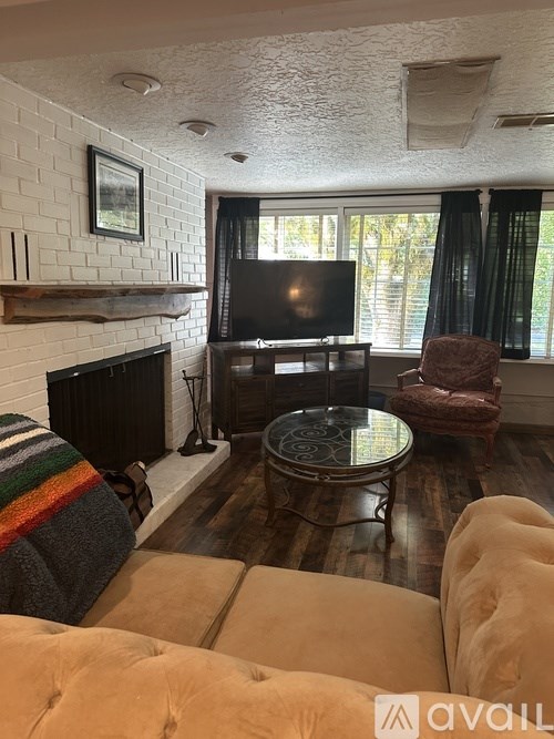 A living room with a fireplace, a chair, and a coffee table.