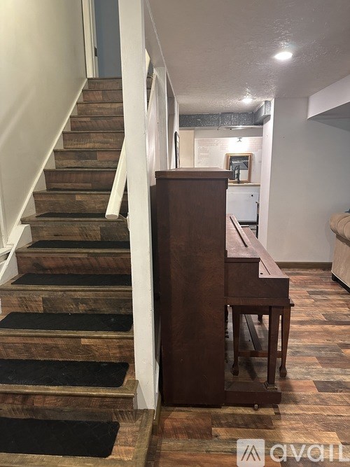 A brown piano sits in front of a staircase.
