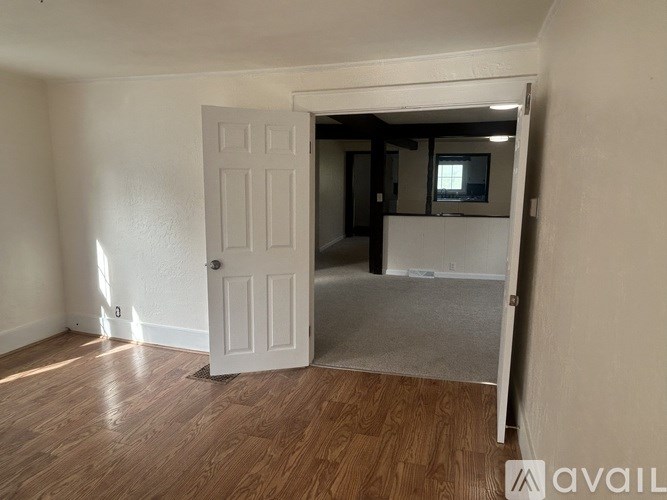 A room with a white door and wooden flooring.