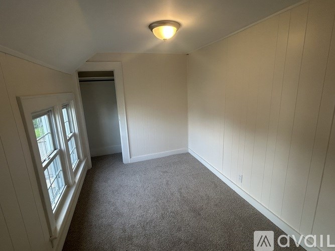 A room with a carpeted floor and a window on the left side.