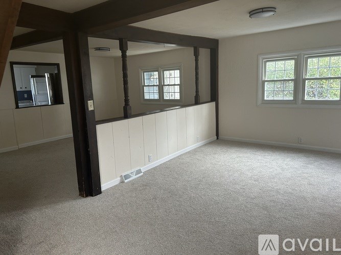 A room with a carpeted floor and a window with a view of trees.