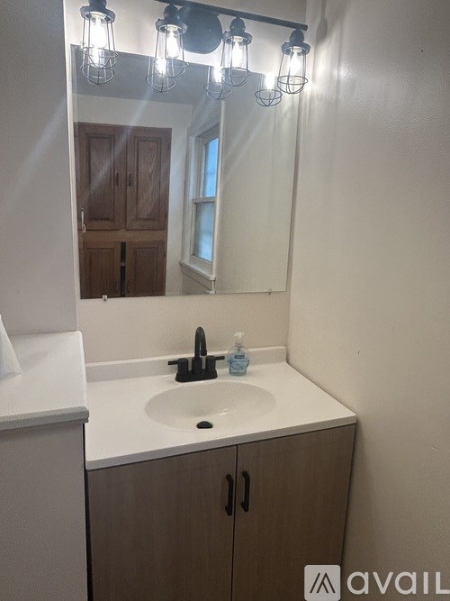 A bathroom with a sink, mirror, and lights.