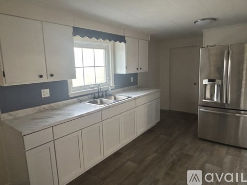A kitchen with white cabinets and a stainless steel refrigerator.