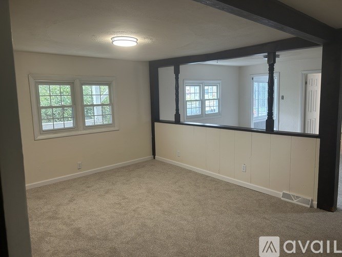 A room with a carpeted floor and a window with a view of trees.