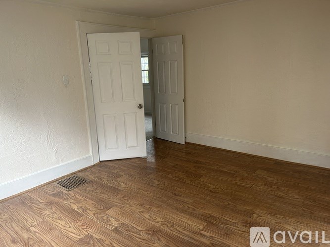 A room with two white doors and wooden flooring.