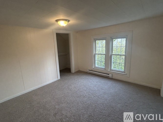 A carpeted room with a window and a door.