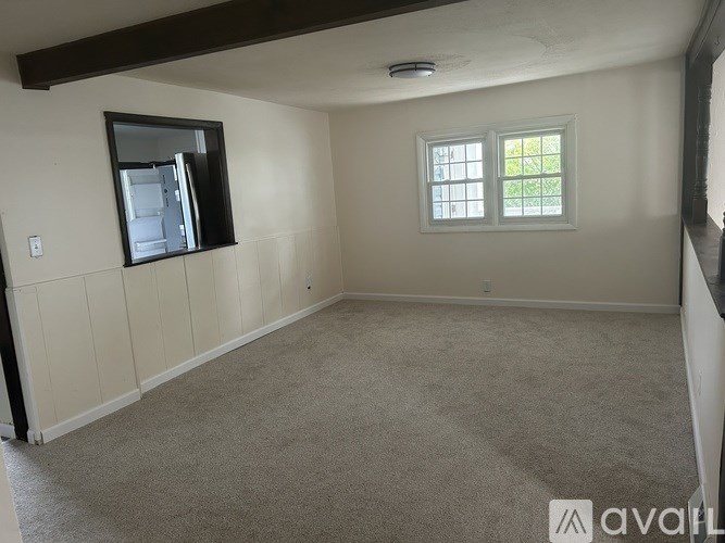 A room with a window and a framed picture on the wall.
