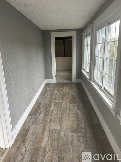 A room with wooden flooring and a doorway leading to another room.