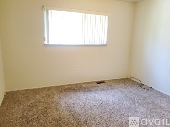 A room with a carpeted floor and a window with blinds.
