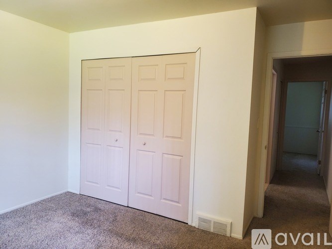 A carpeted room with a white door and a wall with a logo that says "AVAIL".