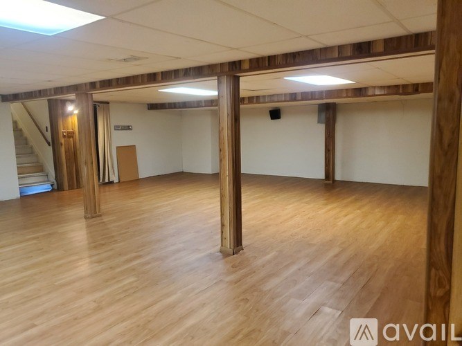 A spacious room with wooden floors and pillars.